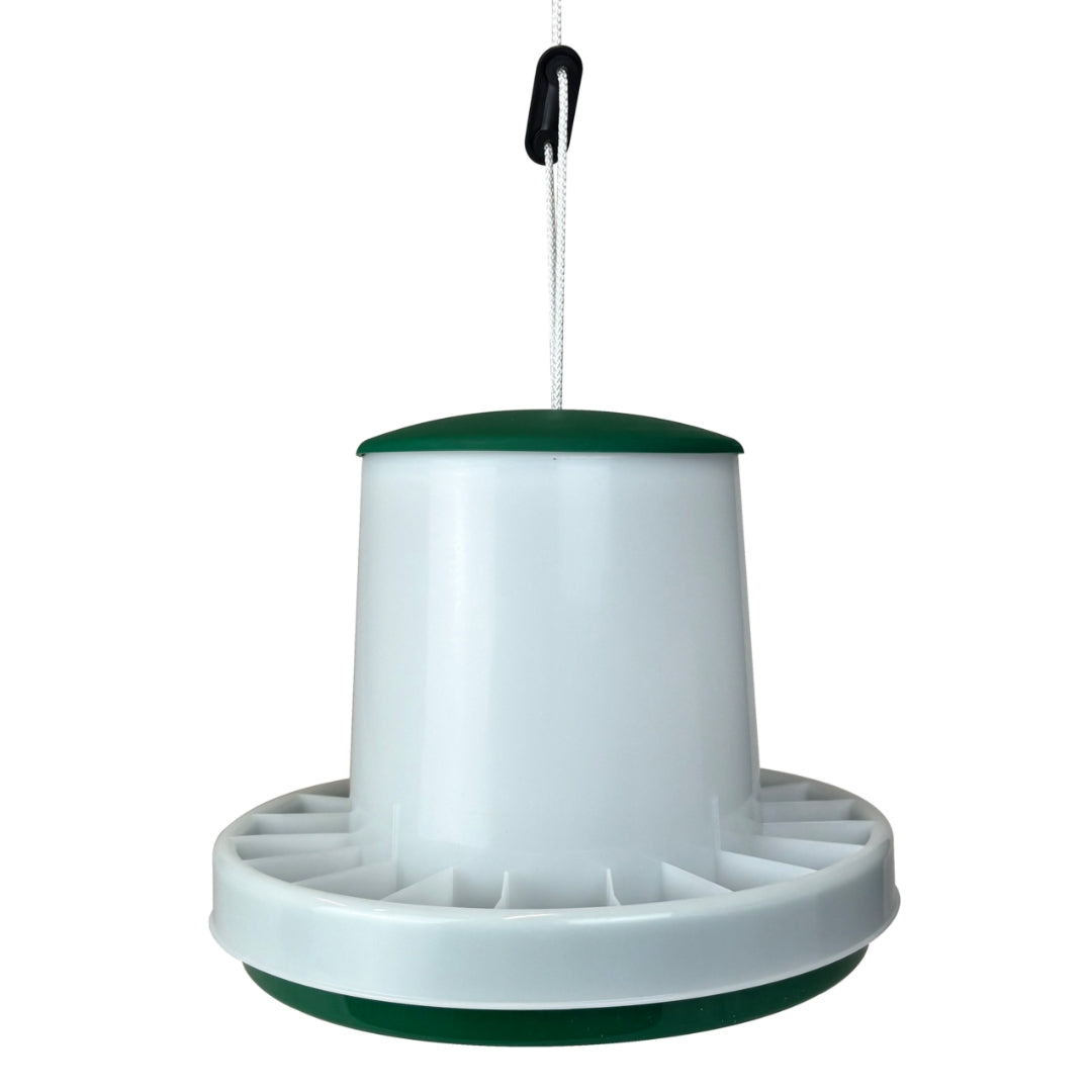 A plastic poultry feeder hanging from a white cord with a black switch, featuring a white body with dark green accents on the top and bottom.