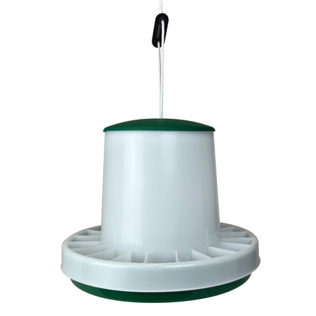 A plastic poultry feeder hanging from a white cord with a black switch, featuring a white body with dark green accents on the top and bottom.